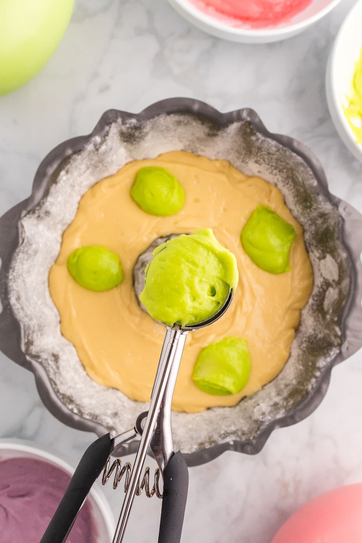 adding colorful batter to yellow cake batter in pan