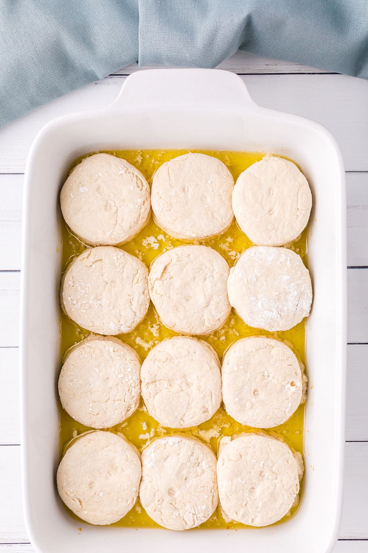biscuits in white baking dish with butter and blue towel in background