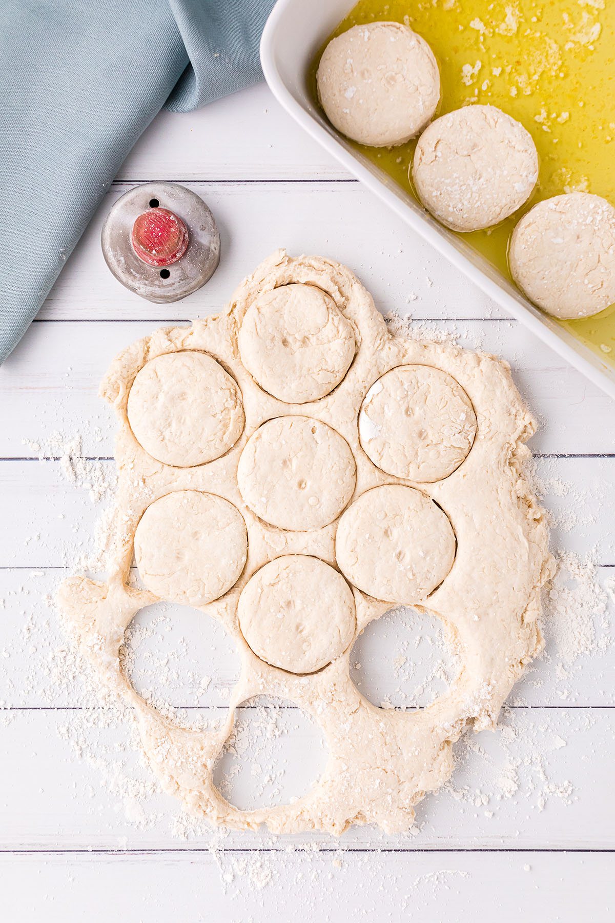 cutting biscuits out of rolled dough and putting them in a buttered dish