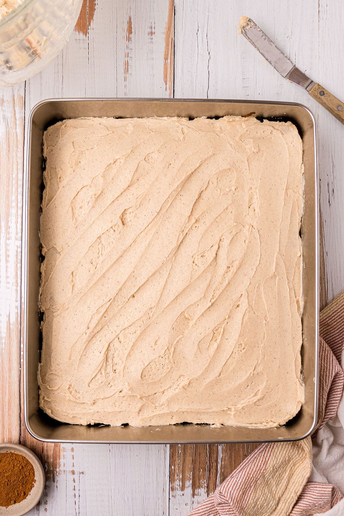 frosting spread on top of an apple cake