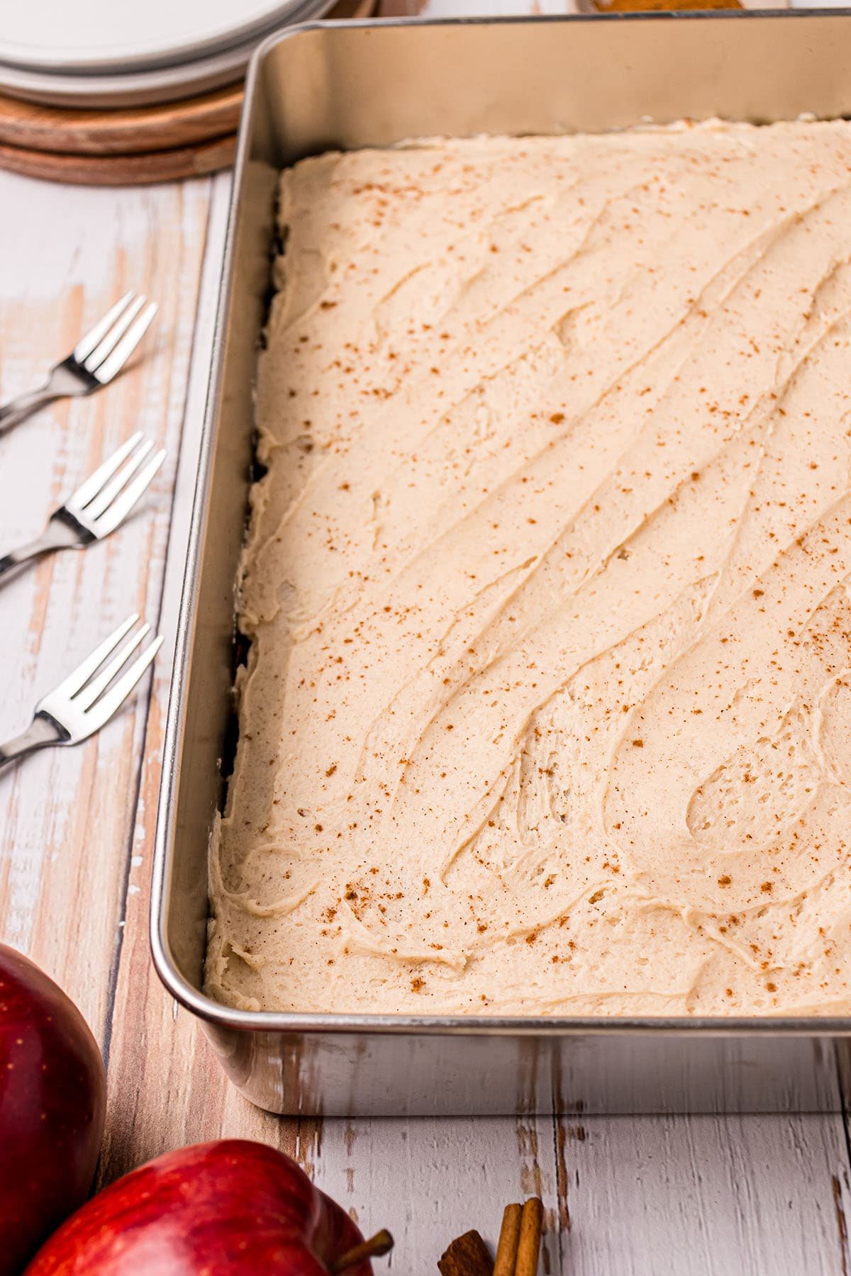 frosted cake in a metal pan dusted with ground cinnamon