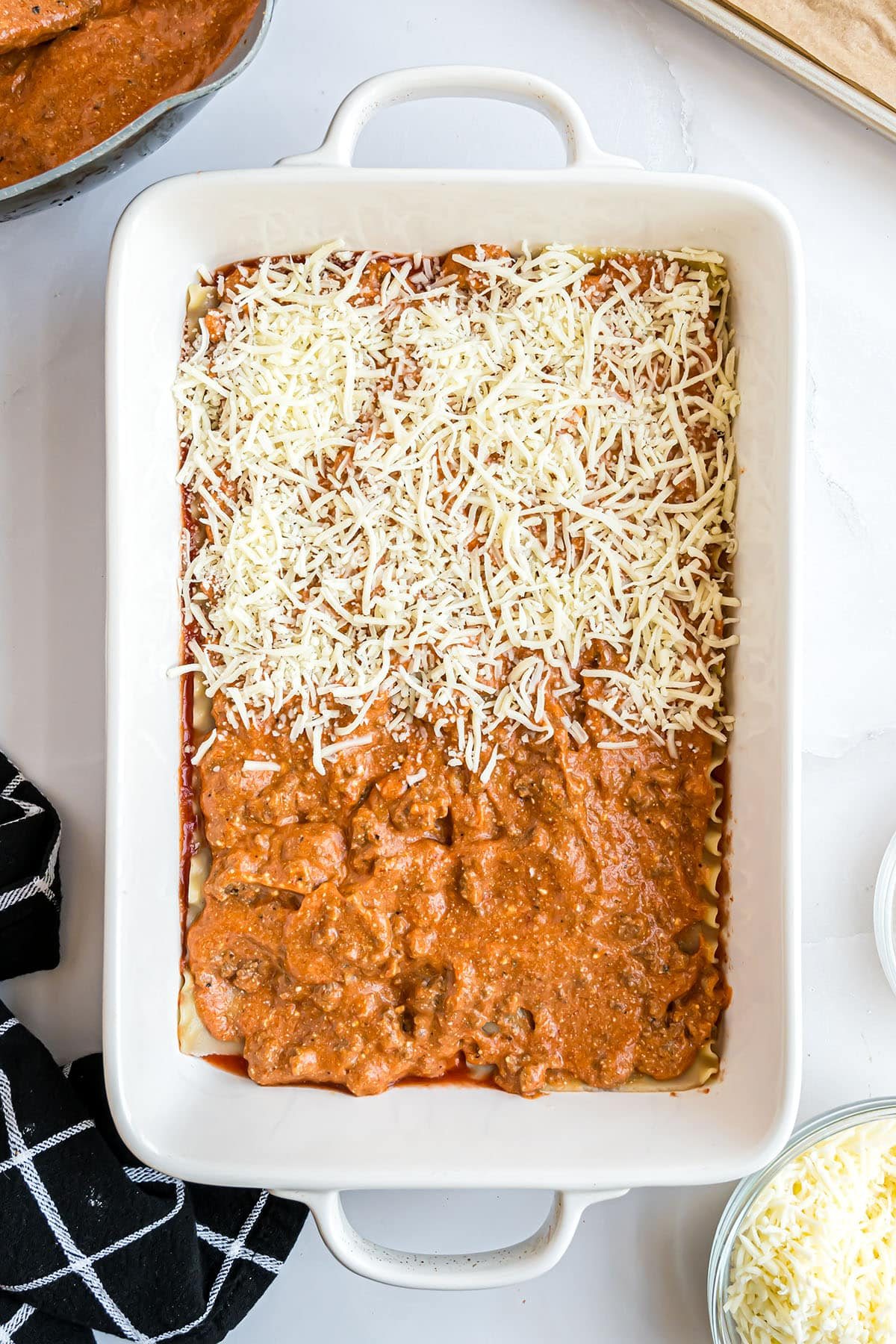 layering meat sauce and cheese with lasagna noodles