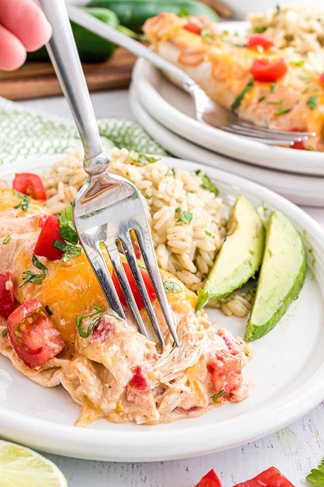 chicken and cheese enchiladas on a white plate with a fork