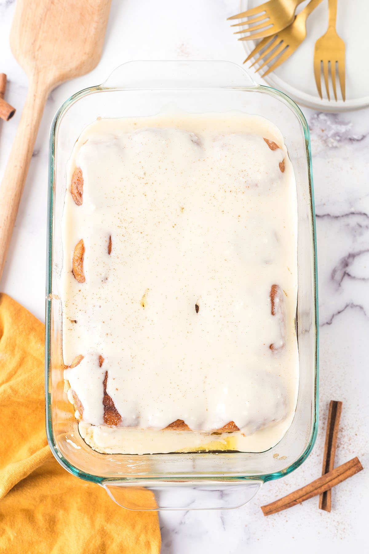 homemade cinnamon rolls in a baking dish covered in cream cheese frosting