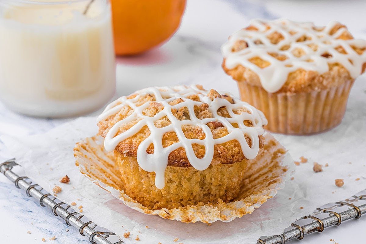 Orange Streusel Muffins on a cooling rack with parchment paper and a bottle of milk in the background