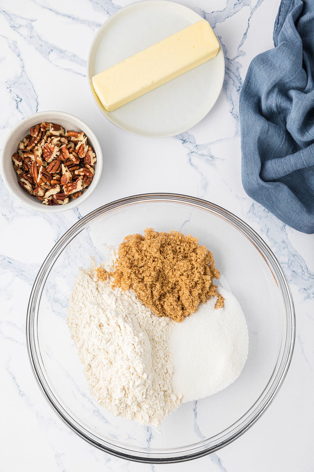 streusel topping ingredients in a glass bowl along side a small bowl of pecans