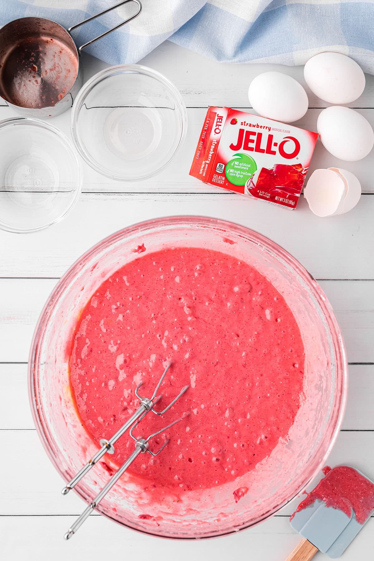 strawberry cake batter with Jello mix in a glass bowl with beaters