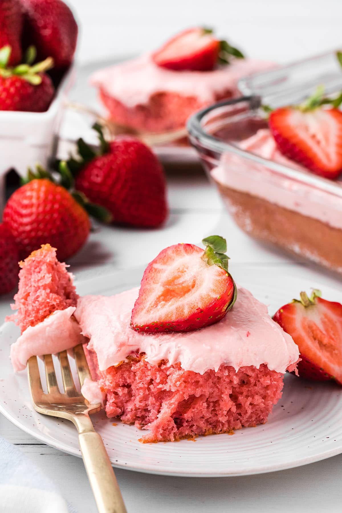 a slice of strawberry cake with a bite on a fork.