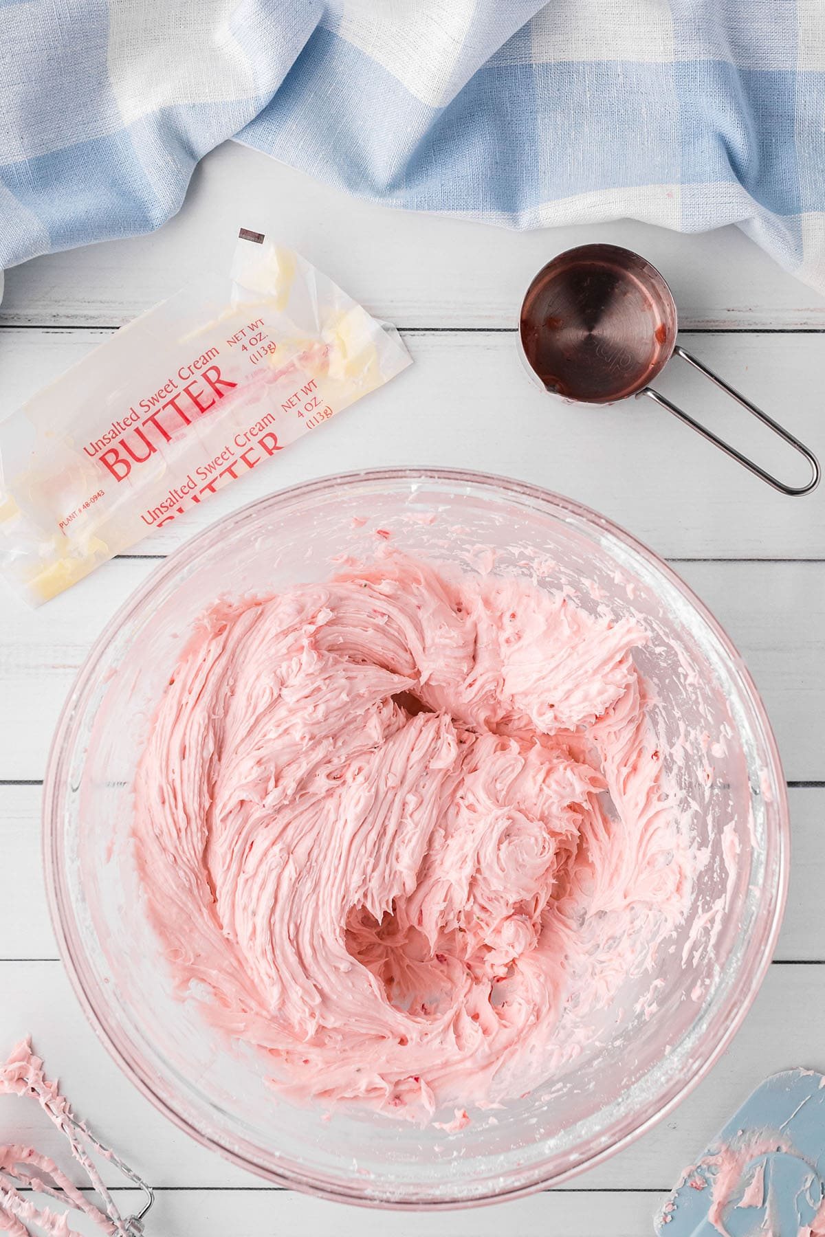 fresh strawberry buttercream frosting in a mixing bowl with a blue towel in the background