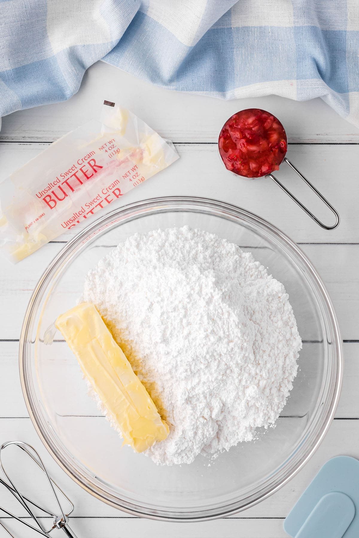 adding butter to powdered sugar in a mixing bowl for butter cream frosing.