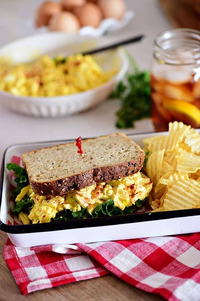 classic egg salad sandwich on a tray with chips