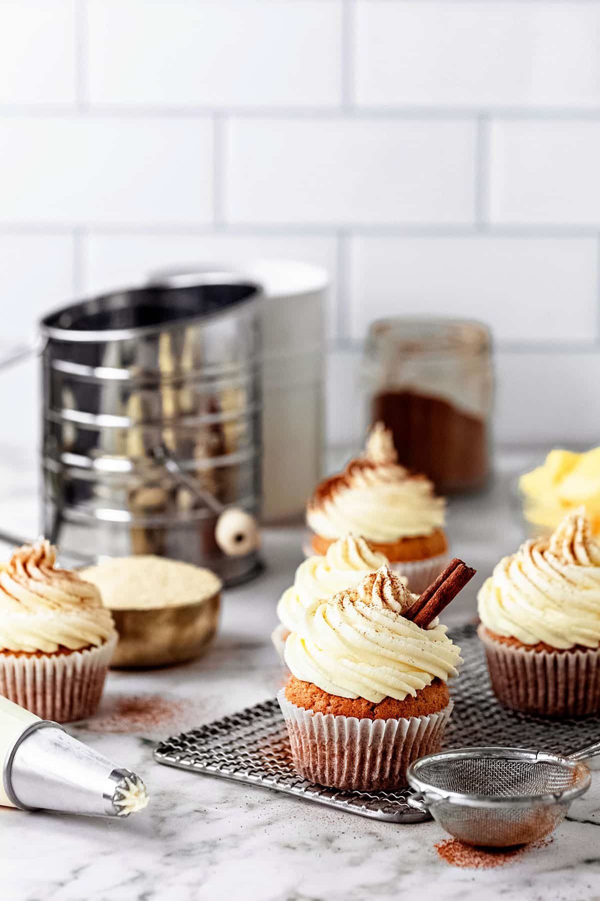 cupcakes on a cooling rack with a piping bag full of frosting