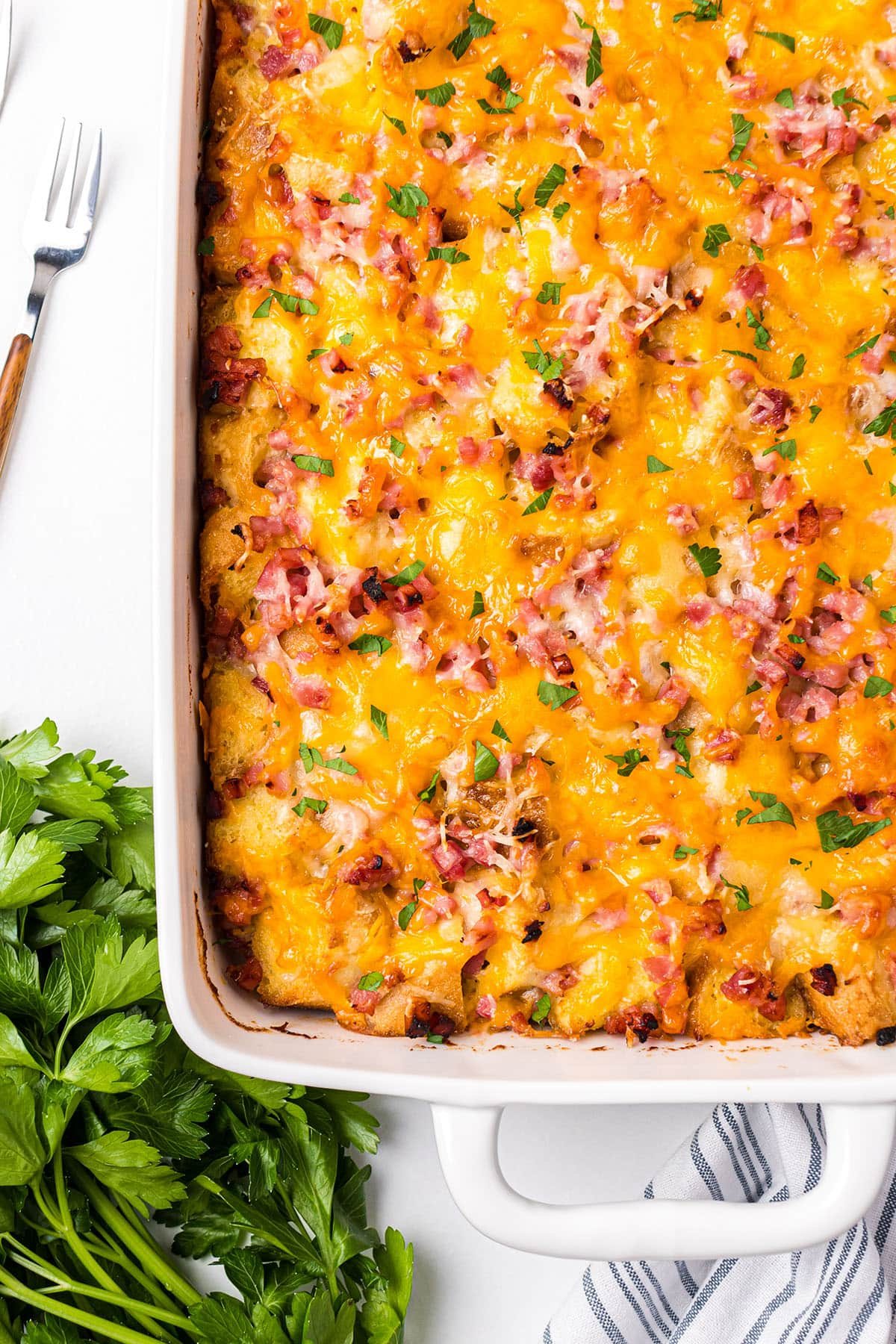 breakfast casserole on a table with fresh parsley next to it.