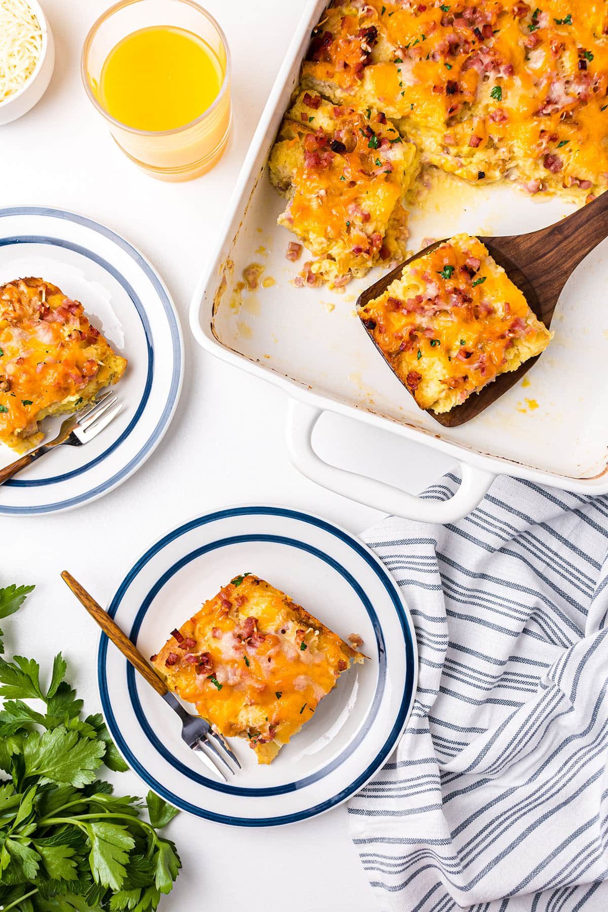 egg casserole on plates and in a white baking dish with a wood spatula