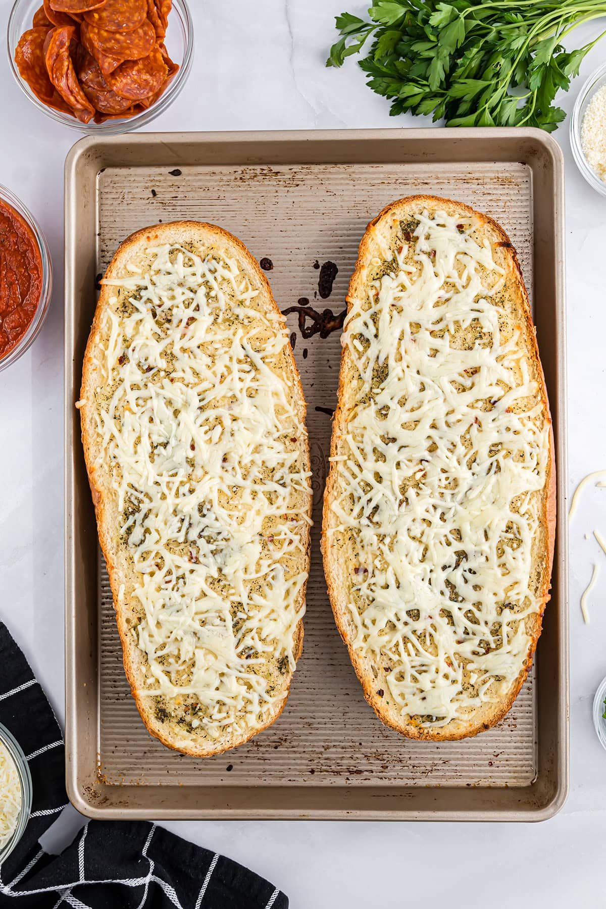 loaf of bread sliced open and toasted with butter and seasonings and melted cheese