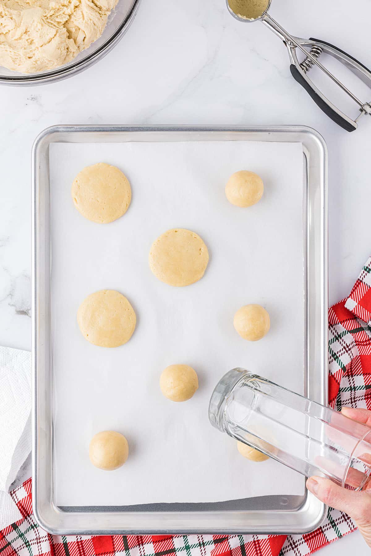 pressing cookie dough balls down with a greased glass to flatten