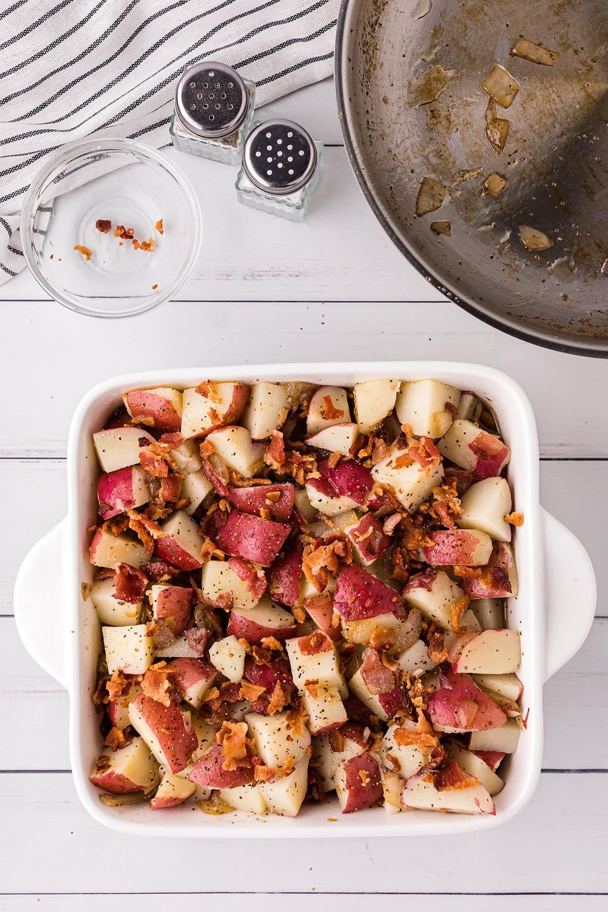 hot potato salad with bacon in a white square baking dish