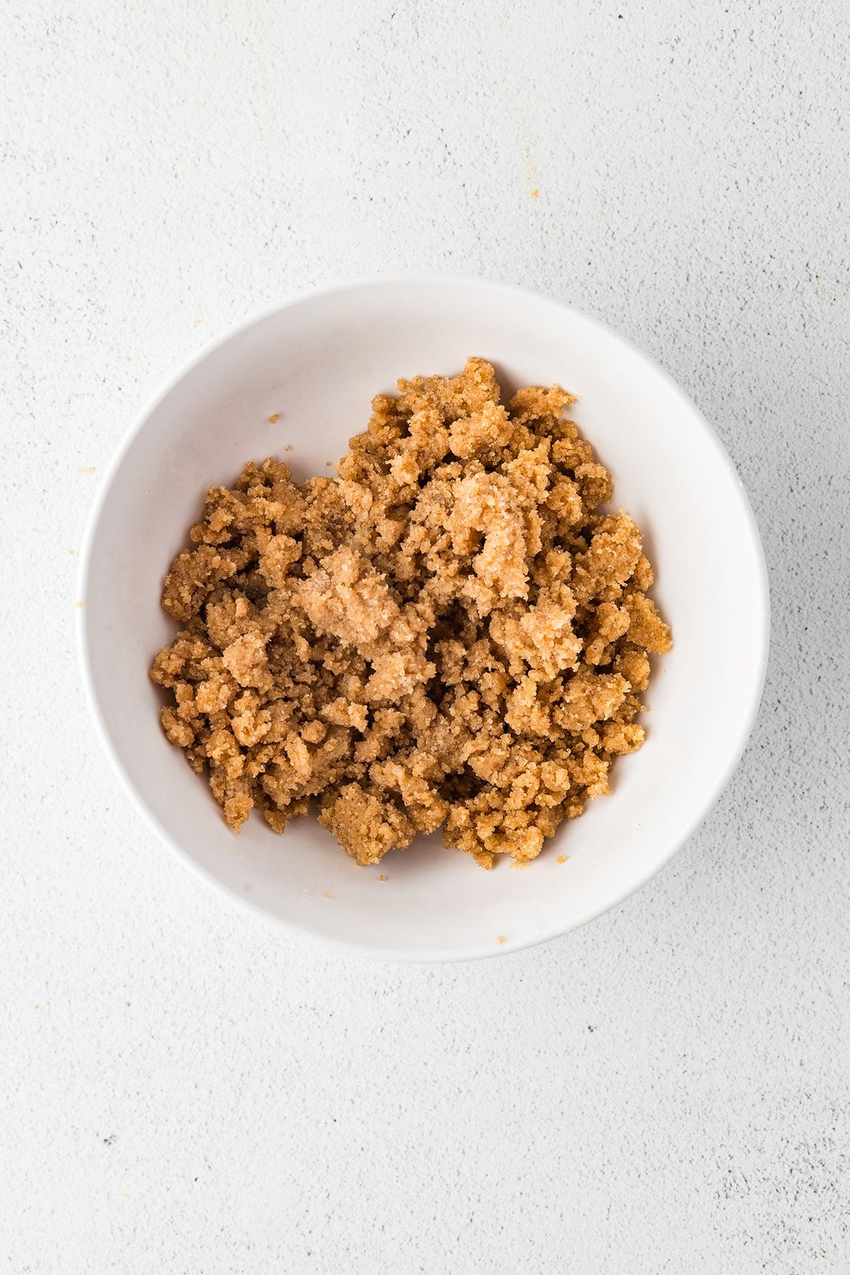 Brown sugar crumble topping for gingerbread muffins in a white bowl.