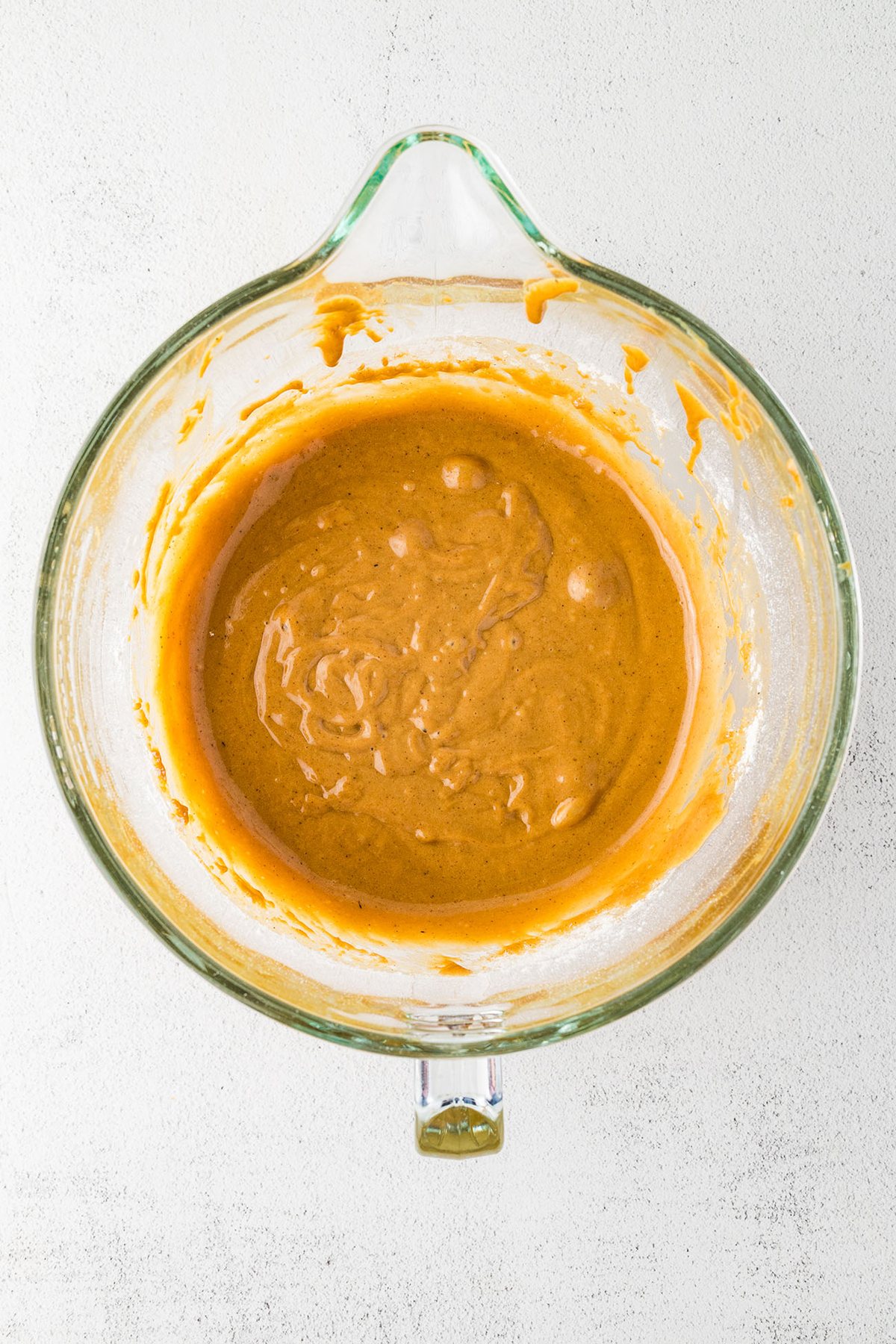 Mixed gingerbread muffin batter in a glass mixing bowl.