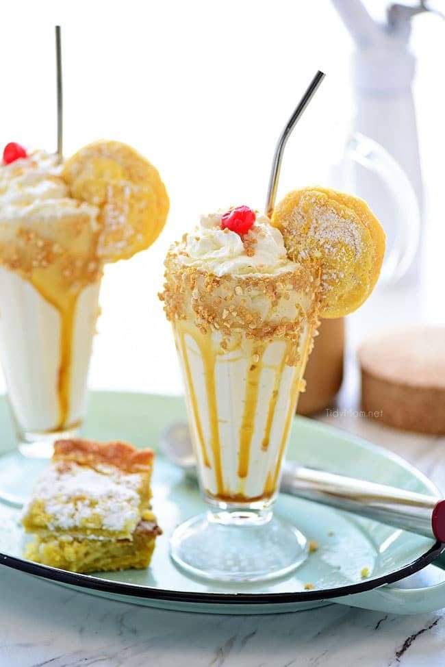 Two glasses ofGooey Butter Cake Cold Brew Milkshake on a tray with a piece of gooey butter cake.