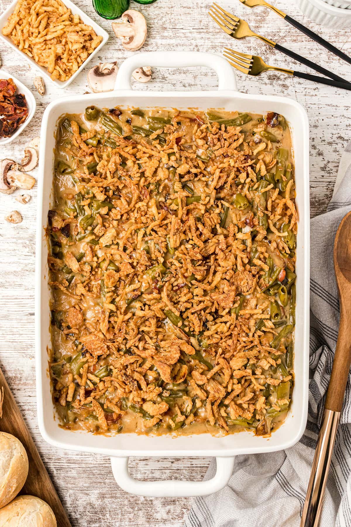 green bean casserole with bacon and fried onion in a white baking dish