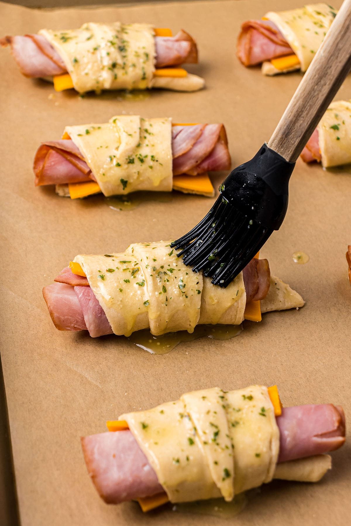 brushing seasoned melted butter on crescent rolls
