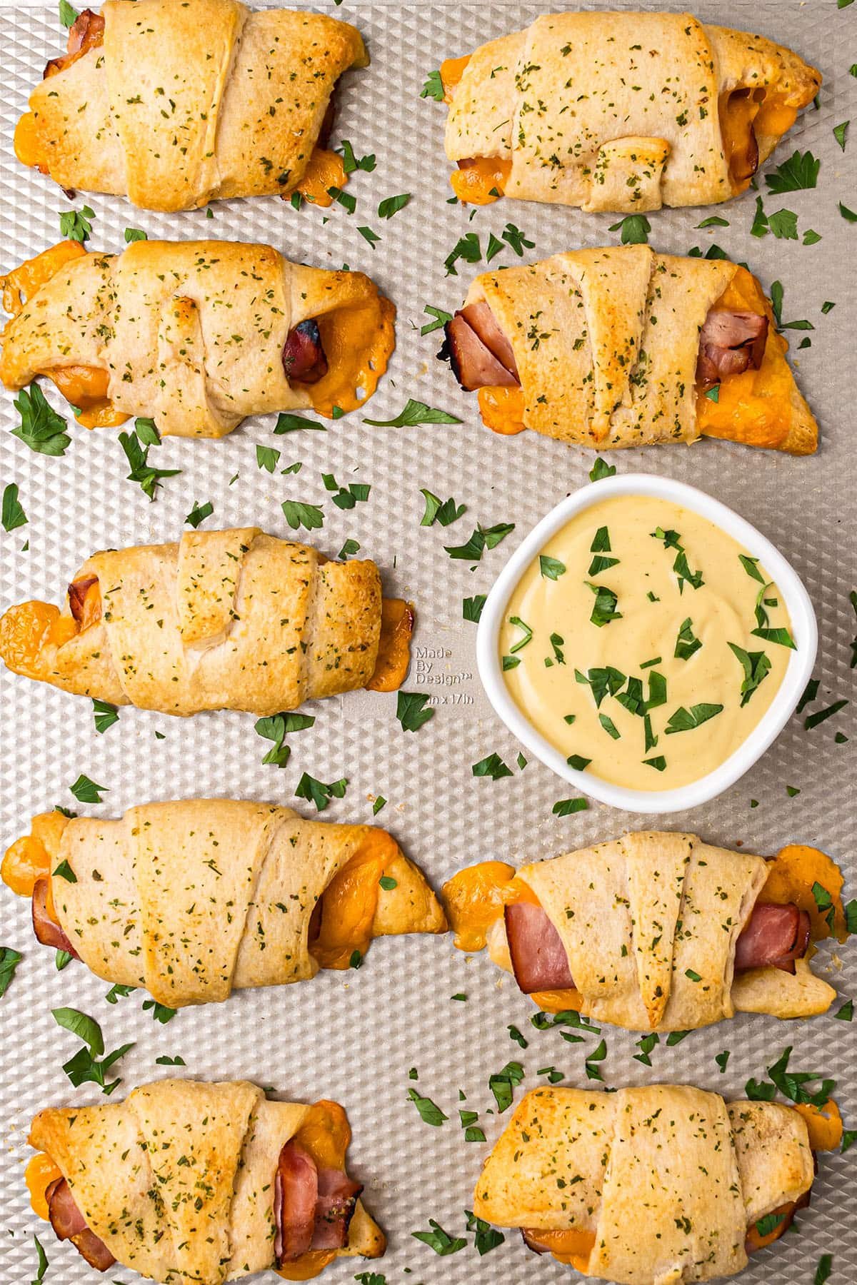 Ham and Cheese Roll-Up Sandwiches on a baking sheet with dipping sauce