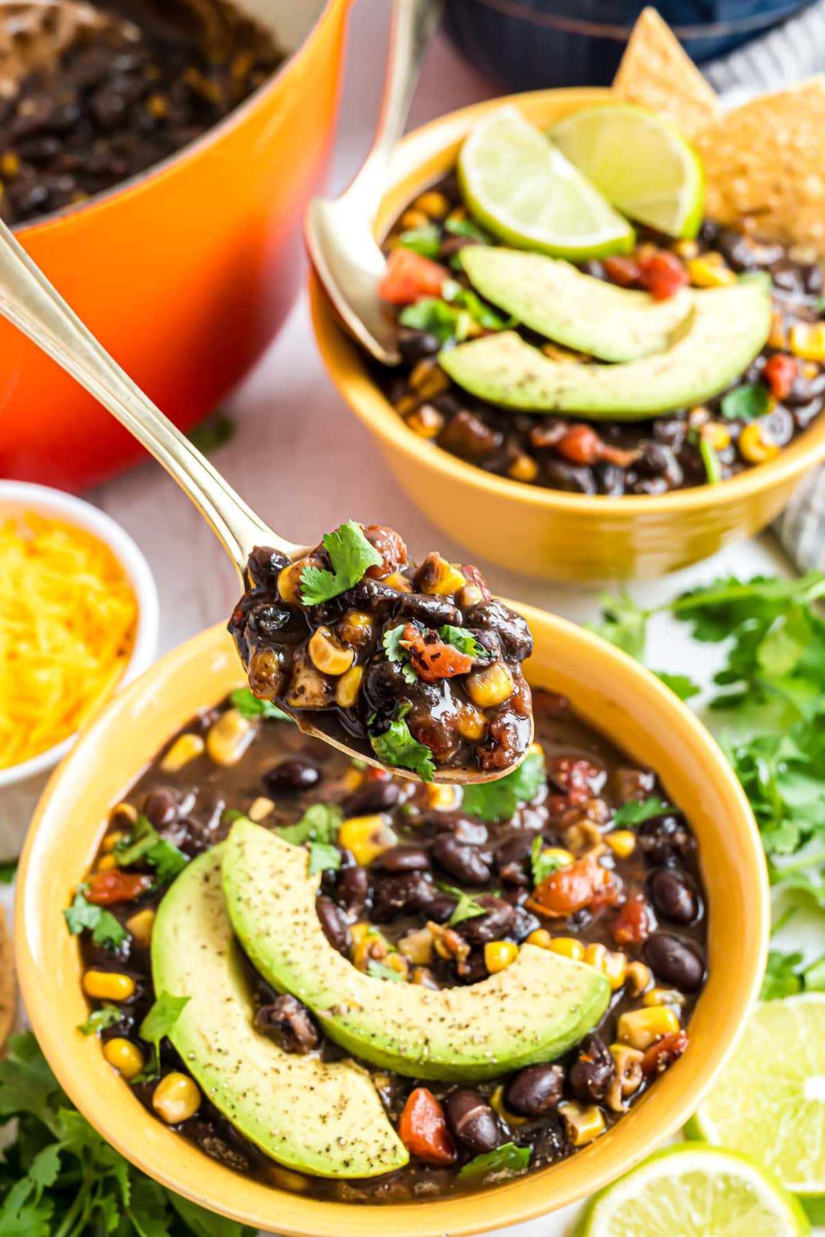 spoon full of black bean soup in a yellow bowl