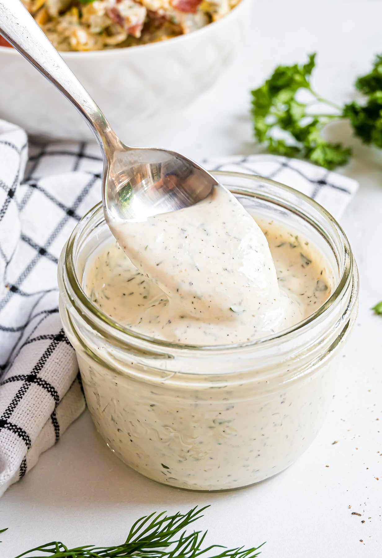 spoon dipping into a jar of homemade ranch dressing