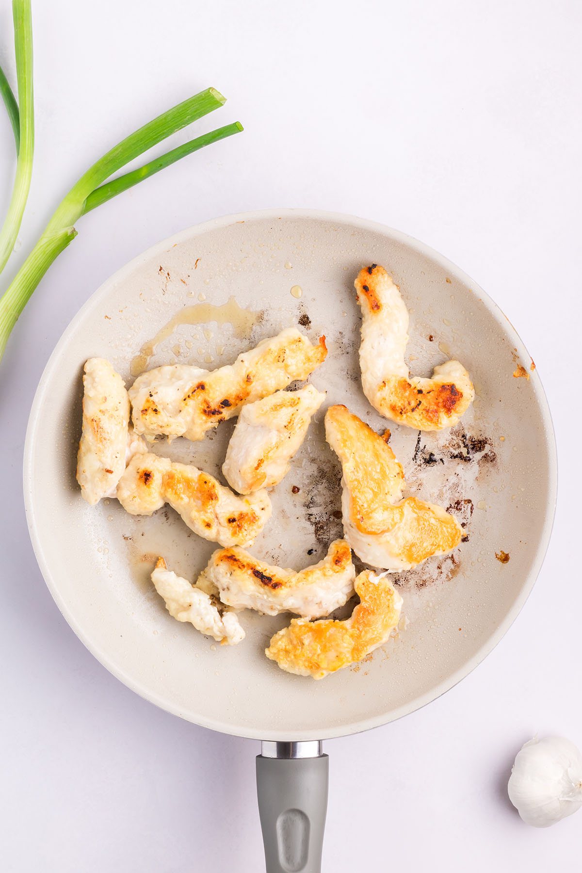cooked chicken tenderloins in a white skillet