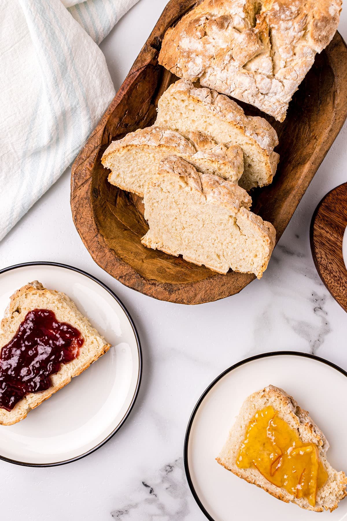 cut loaf of bread and two slices on plates with jam
