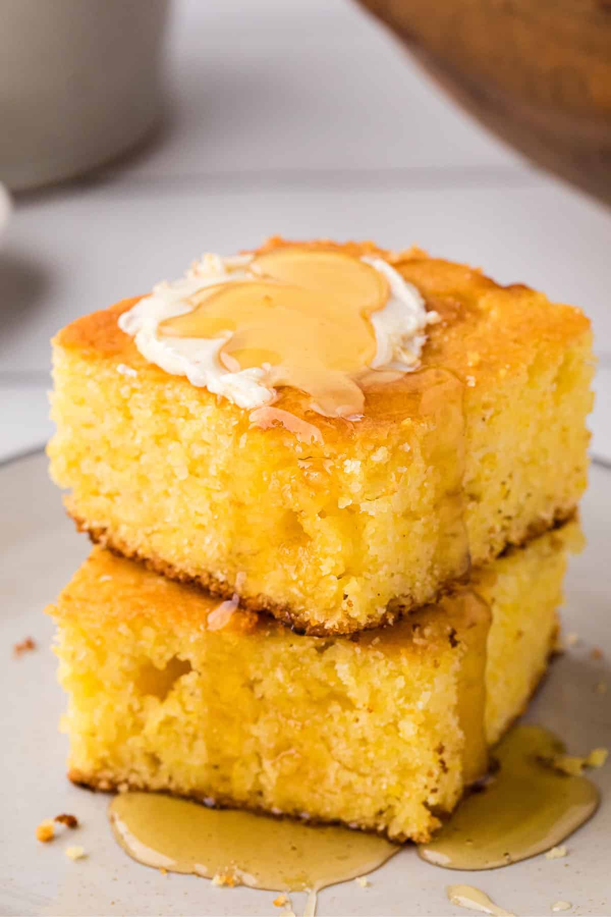2 servings of cornbread stacked and topped with butter and honey