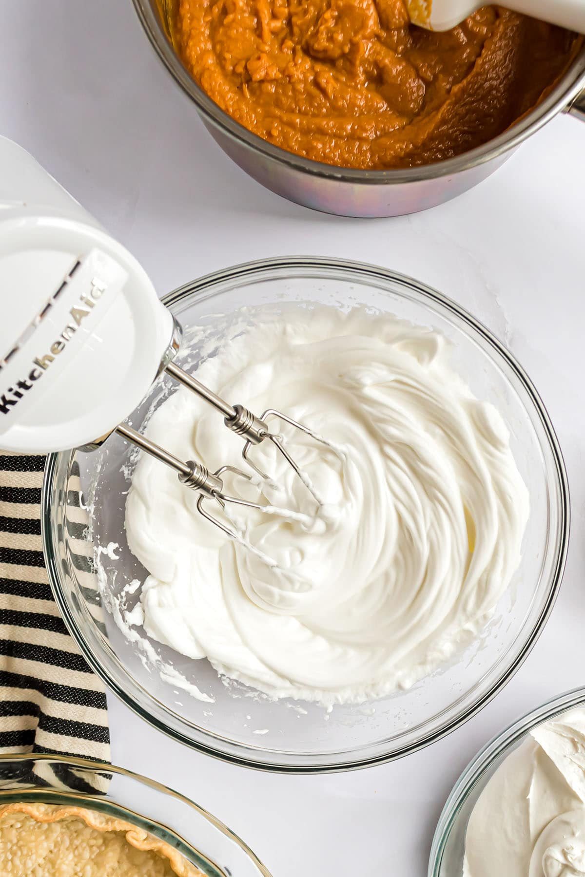 mixing up meringue in a glass bowl with an electric mixer