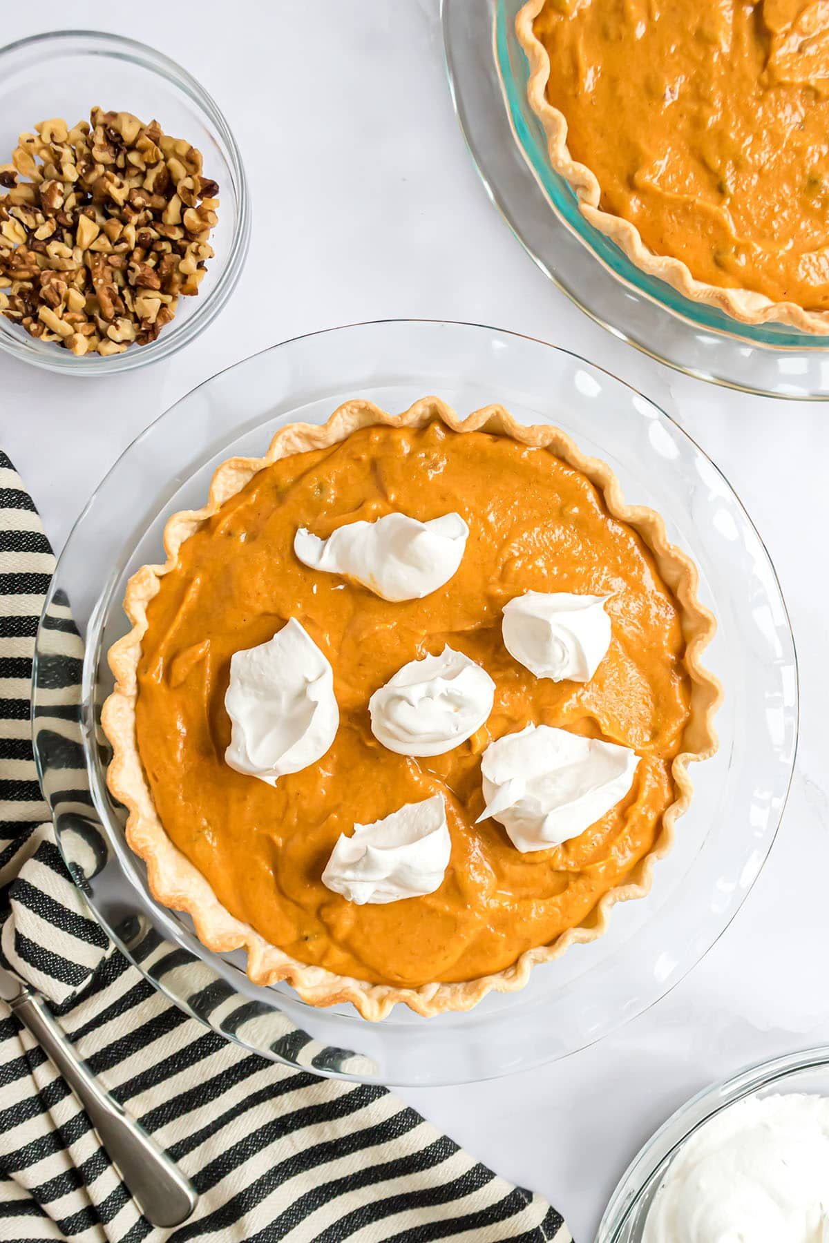 dollops of Cool Whip over pumpkin pie filling in a glass pie dish