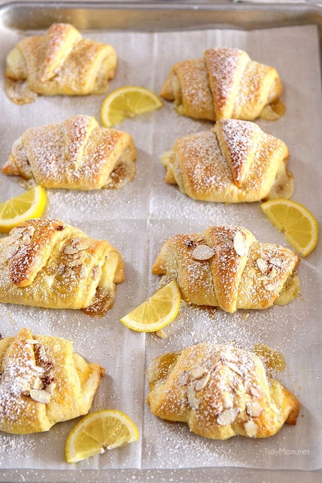 lemon cheesecake crescent rolls on a baking sheet with fresh lemon slices
