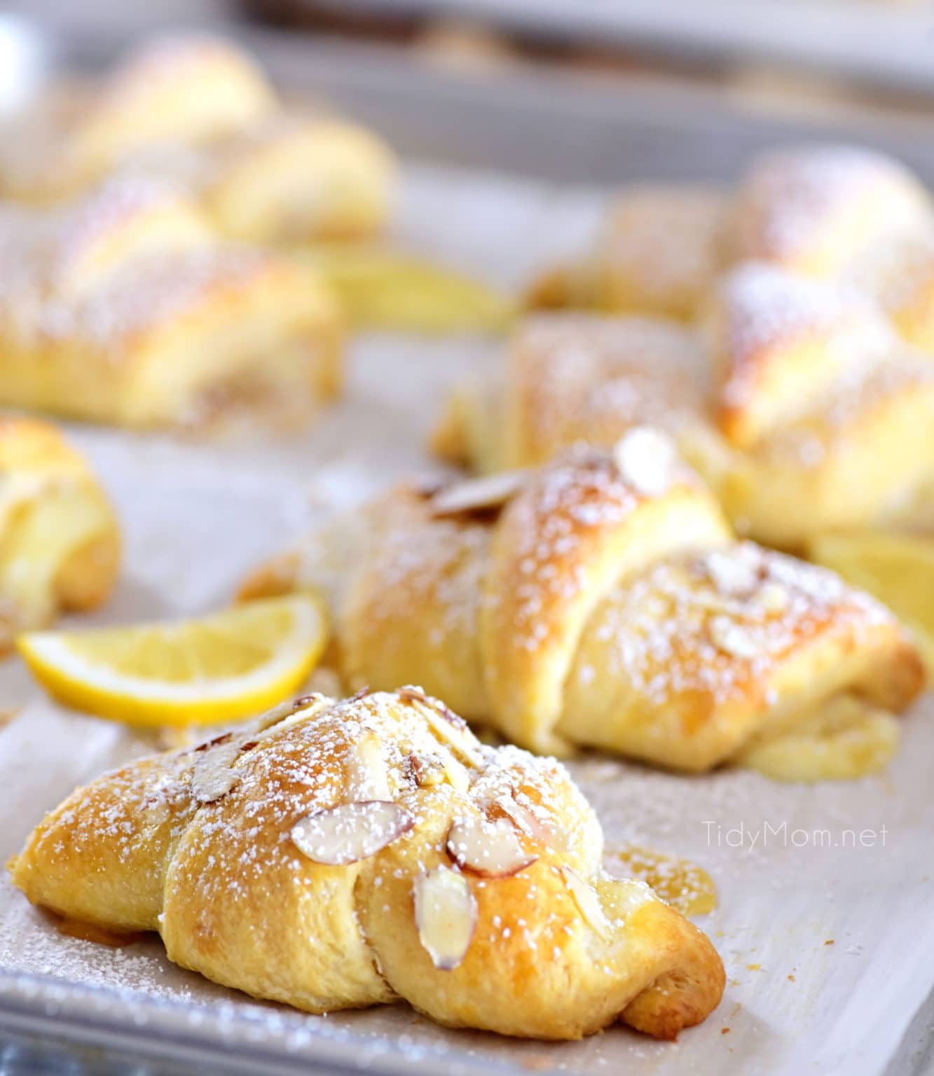 lemon cheesecake crescent rolls with almond slices on a sheetpan