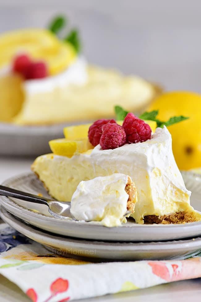 a slice of lemonade pie on a plate with a bite of the pie on a spoon