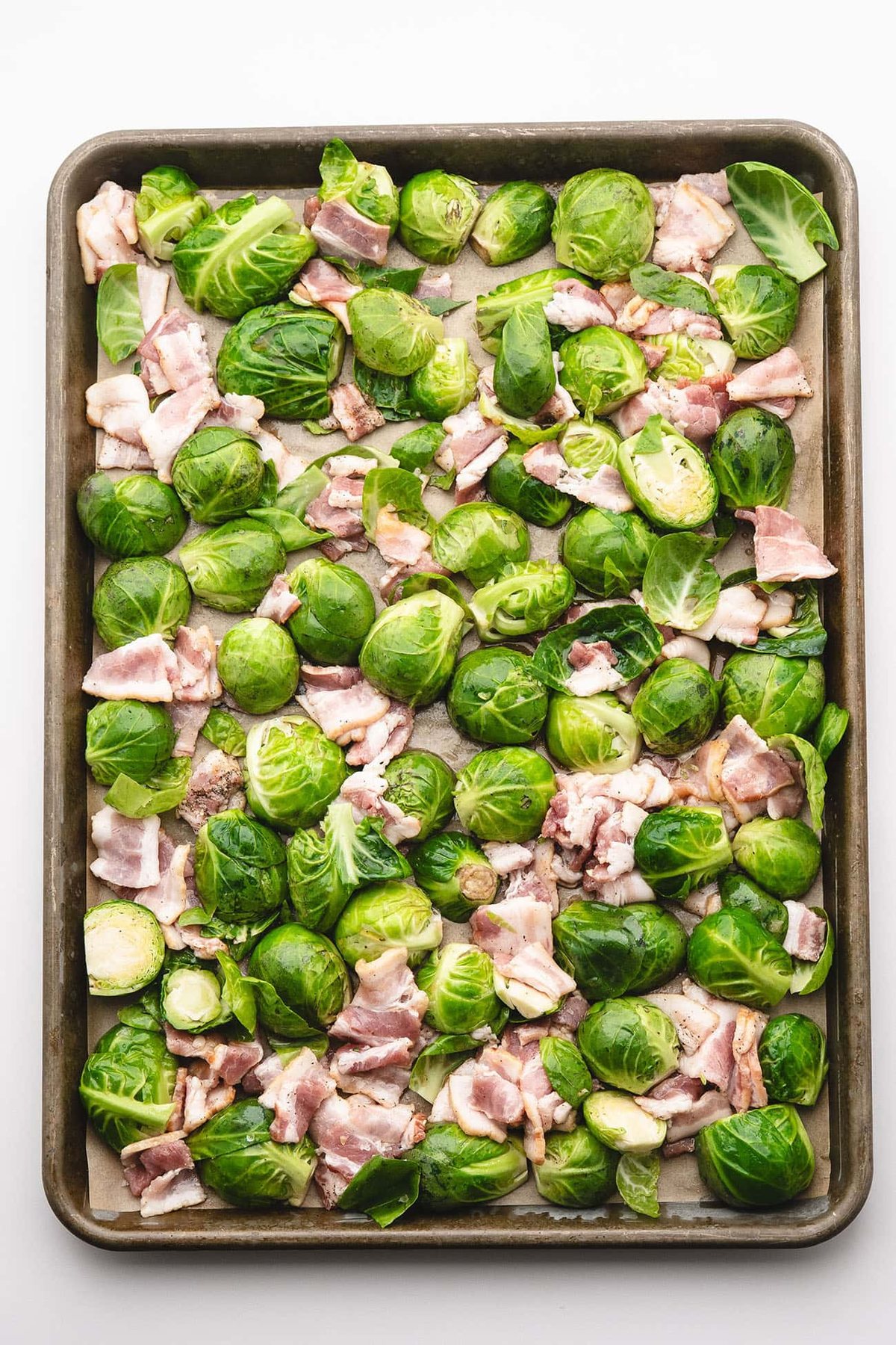 sprouts and chopped bacon arranged on a sheet pan
