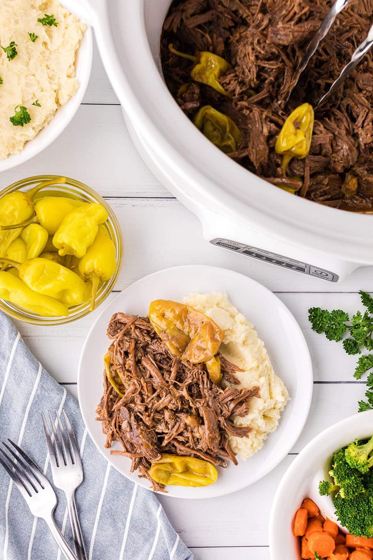 pot roast with pepperoncini and mashed potatoes on a plate by a slow cookier