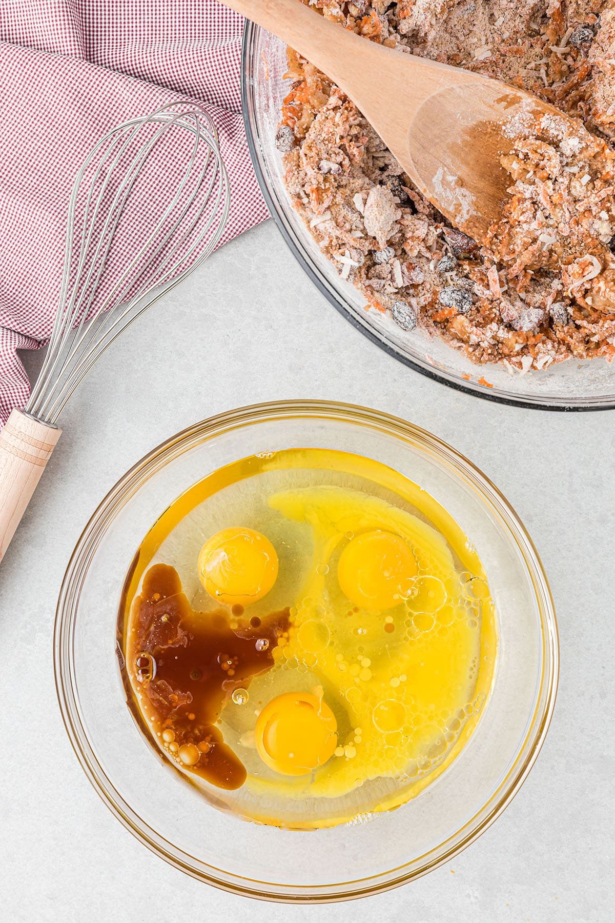 2 mixing bowls with muffin batter and a red and white towel