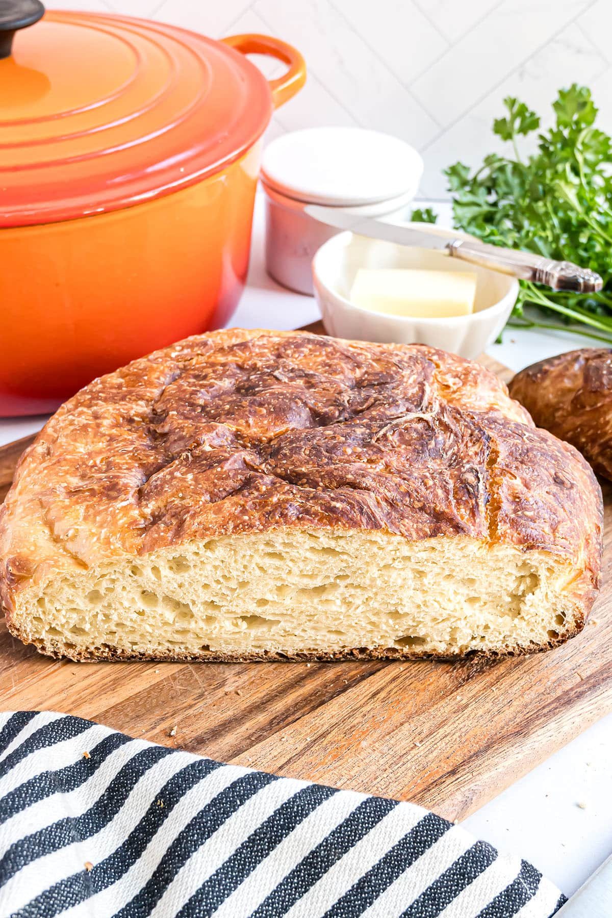 no-knead dutch oven bread loaf with a black and white towel in the foreground