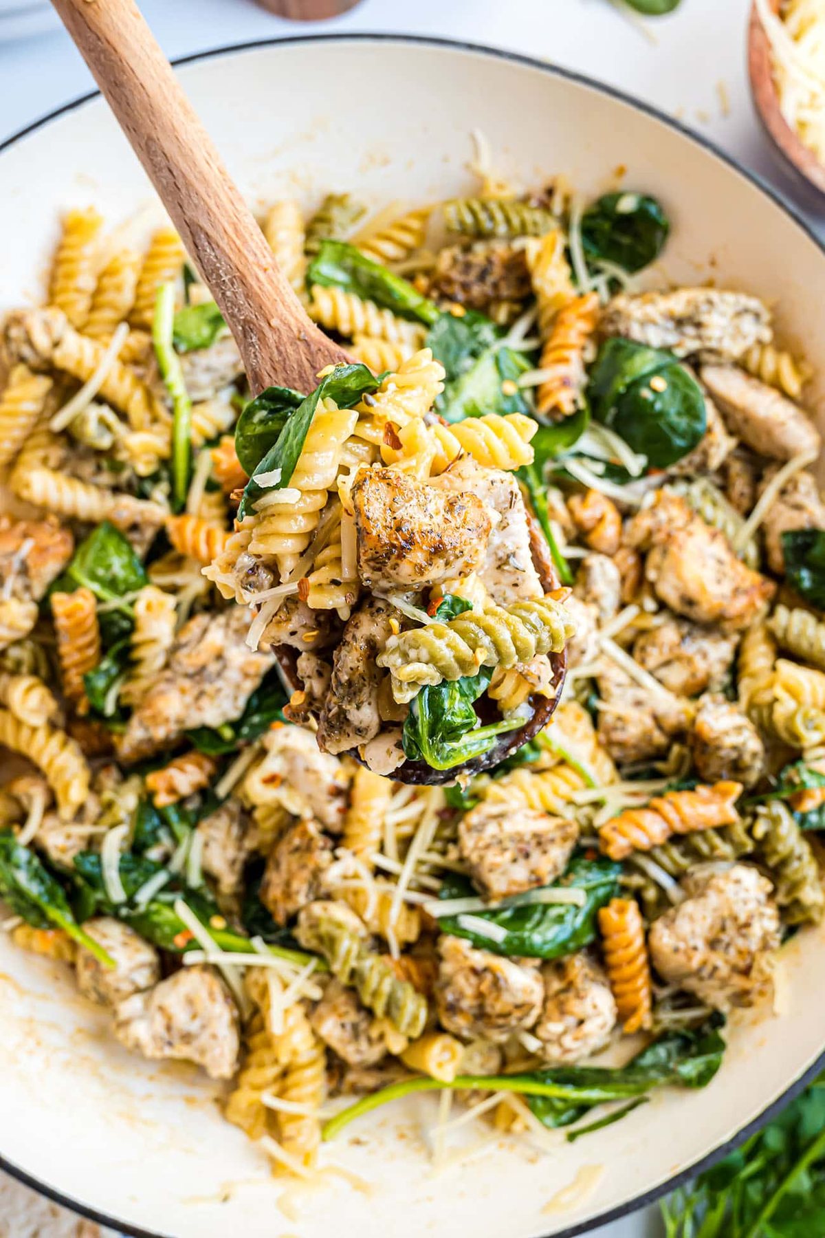 One pan creamy herb and garlic chicken pasta in skillet with wooden spoon