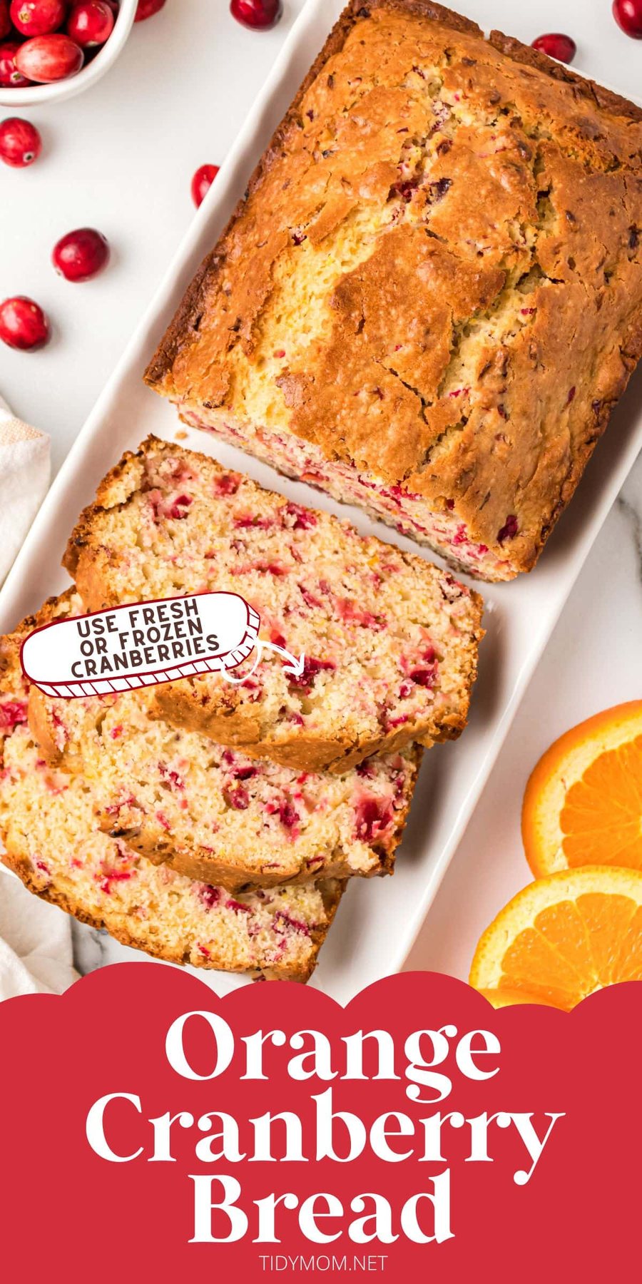 Sliced loaf of cranberry bread with fresh cranberries and orange slices