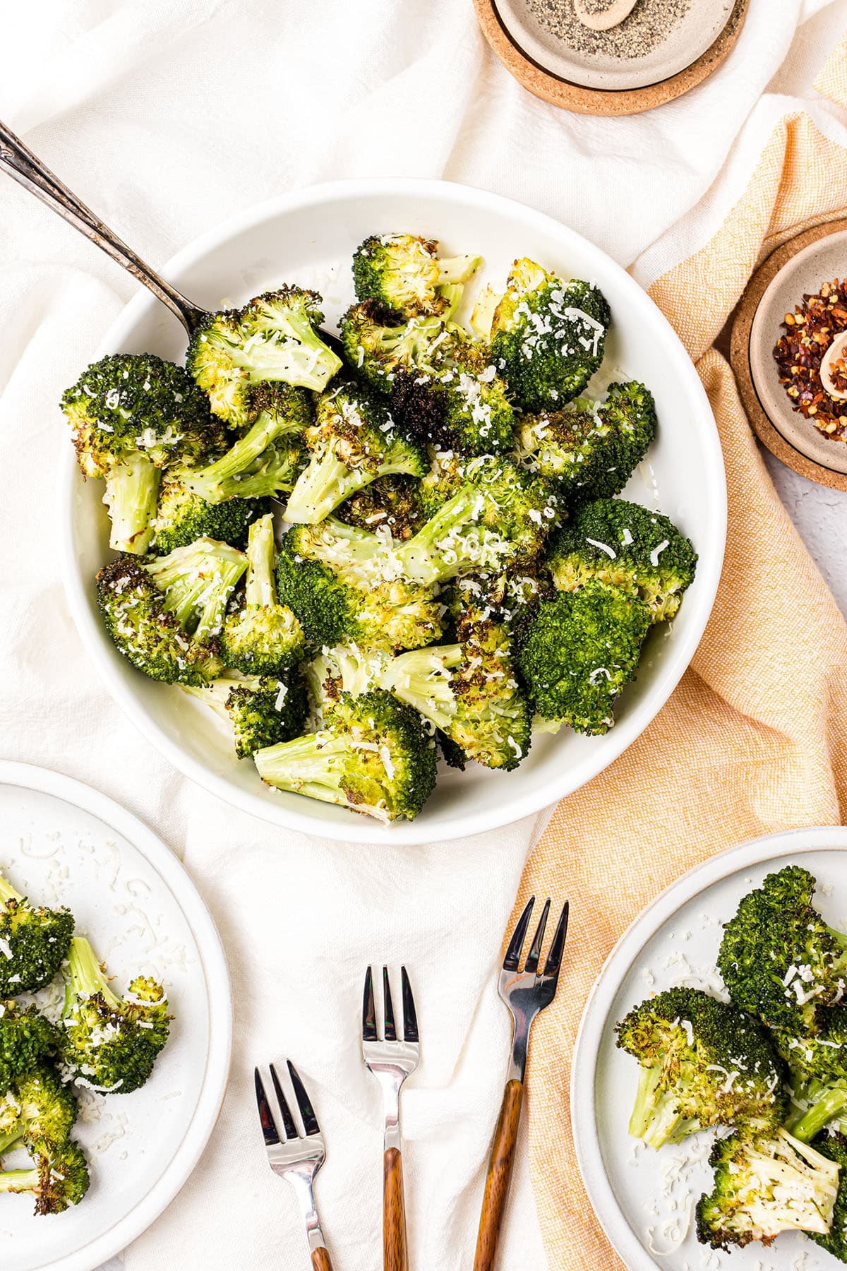 a bowl of oven roasted broccoli with a serving spoon