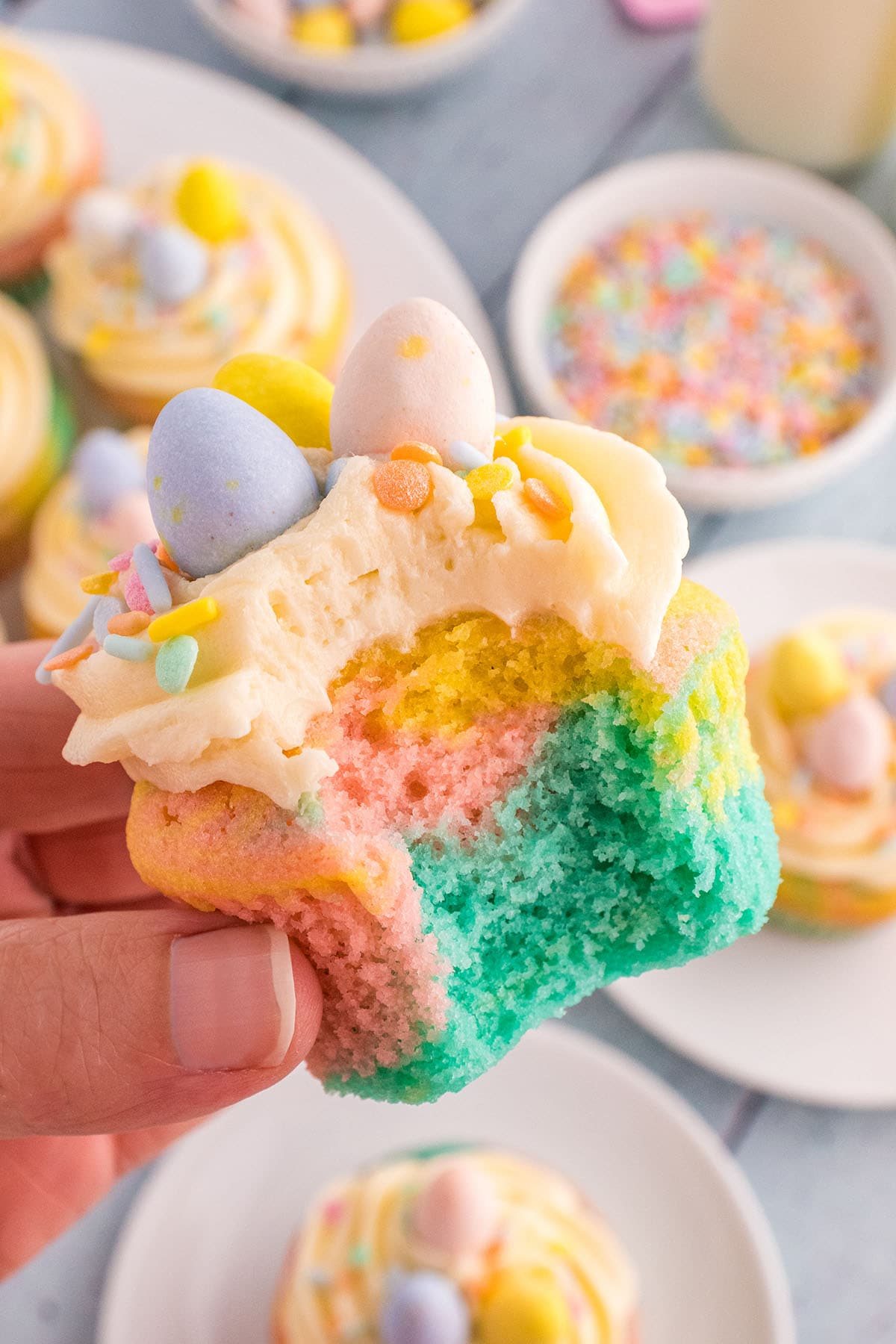 hand holding a Spring cupcake with a bite taken,
