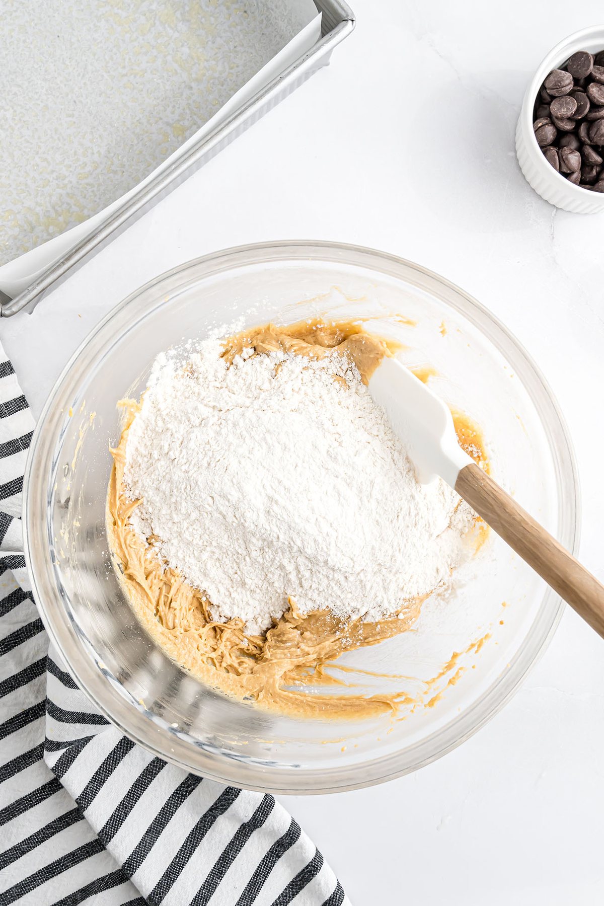 Stirring dry ingredients into the wet peanut butter mixture with a rubber spatula until combined.