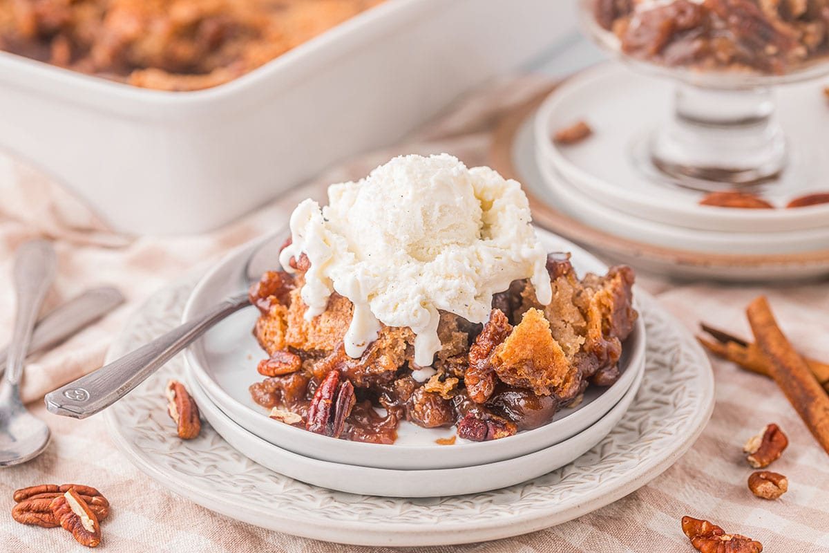 serving of pecan pie cobbler on a plate topped with vanilla ice cream