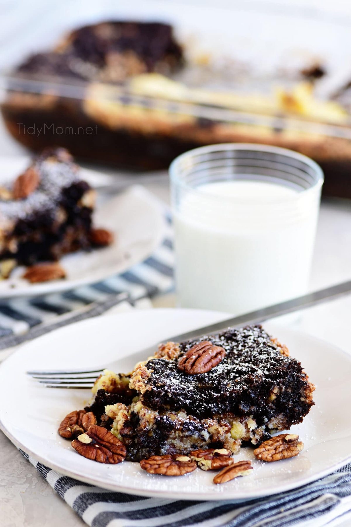 Chocolate Pecan Pie Gooey Butter Cake on a white plate with a glass of milk