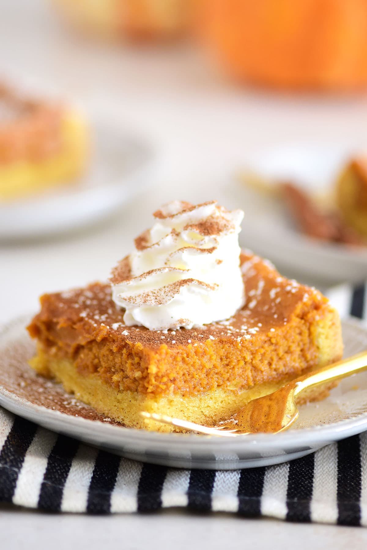 a serving of pumpkin dessert on a plate with cool whip and a gold fork