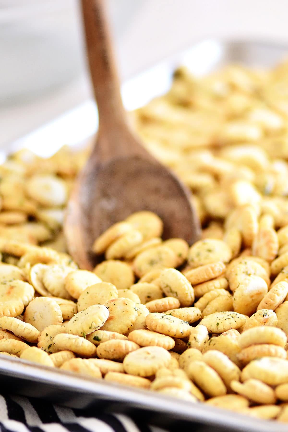 stirring oyster crackers on a baking sheet lined with parchment paper